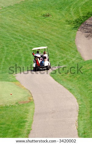 Golfers - Golfers using a golf cart to get around the winding roads and hills of a golf course.