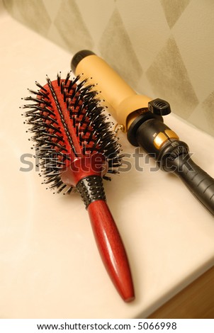 Hairbrush and Curling Iron - a red hairbrush and a gold electric curling iron on the counter top.
