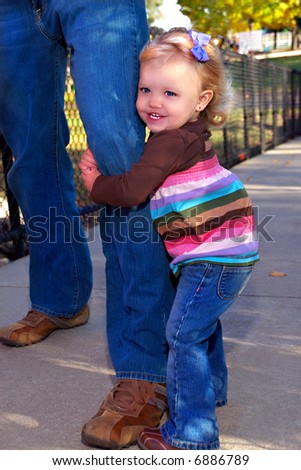 My Daddy And Me - An 18 month old toddler girl hugging her daddy\'s leg as they play in the park.