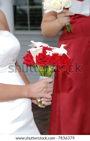 Bride holding her bouquet of red roses and white lily flowers.