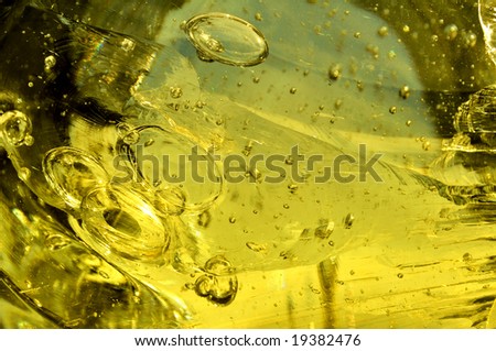 The surface of a yellow rock that looks like glass with bubbles and scratches, for use as a background or overlay.