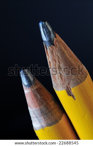 Macro shot of two sharpened lead pencils against a black background.
