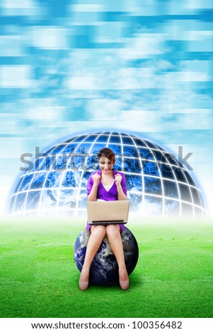 Beautiful woman hold notebook computer and digital world background on the grass field : Elements of this image furnished by NASA