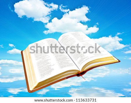 A photo of an open Bible with Blue sky and white clouds with reflection in water