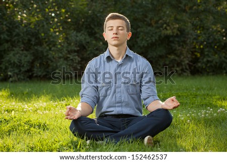 Teenager boy meditating and relaxing in a park