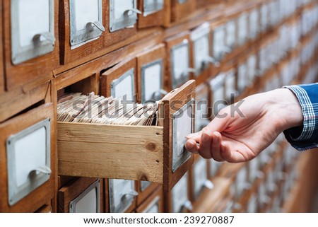 woman hand opening a file cabinet drawer full of files