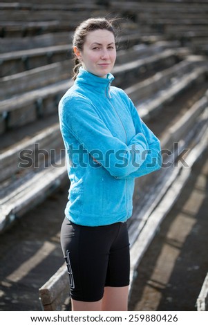 young woman exercises jogging and running on athletic track on stadium on a track and among stadium rows