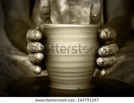 Close-up of potter\'s hands with the product on a potter\'s wheel