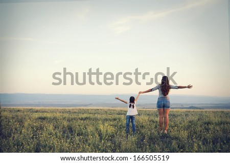 Mom and daughter go off into the distance on a beautiful meadow