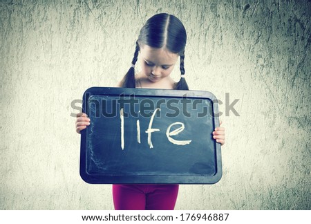 Pretty girl with braids holding board with an inscription Life