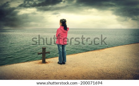 Sad little girl looks at the sea