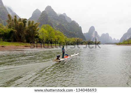 A Man driving a boat on LiJiang River, Guanxi, China