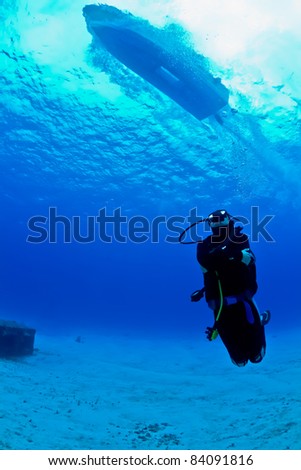 A young female scuba diver looks up as a speeding boat zooms over head on a dive in Mexico.