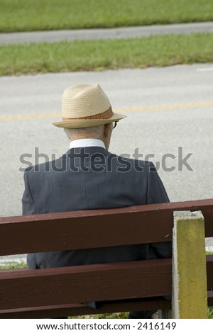 elderly man sitting on wooden bench waiting for a bus