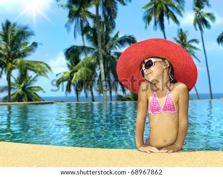little girl in the swimming pool in hat and sun glasses