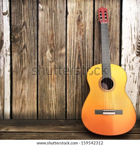 Acoustic wooden guitar leaning on a wooden fence. Advertisement with room for text or copy space.