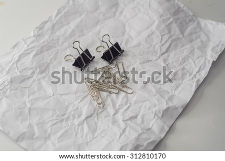 white crinkled paper with black metal clamp and silver clip