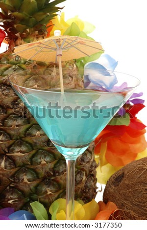 Blue cocktail set against fresh pineapple and colorful flowers.