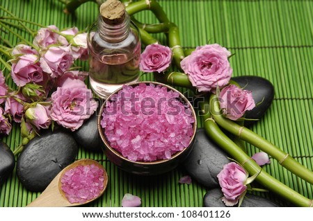 Branch rose with salt in bowl and massage oil ,grove on green mat