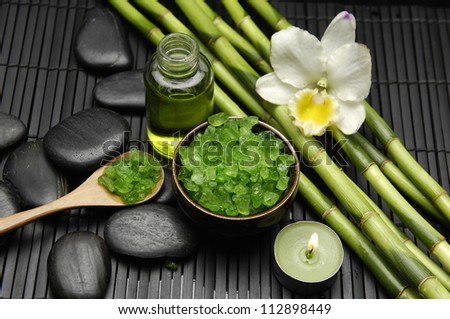 White orchid with salt in bowl and massage oil ,grove on green mat