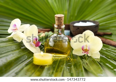 Spa set with yellow orchid flower ,spa oil salt in bowl ,candle on palm leaf