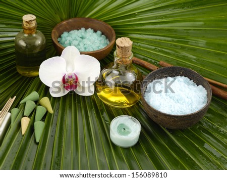 Orchid with massage oil and salt in bowl,candle, towel on green mat