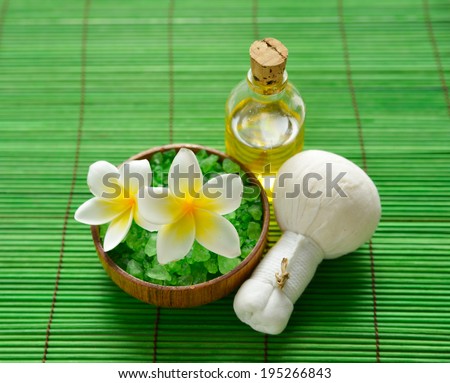 frangipani with salt in bowl with massage oil and on green bamboo mat