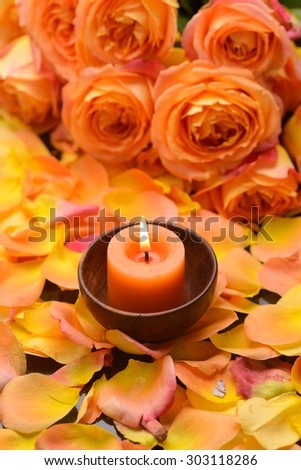 Rose, petals with candle in wooden bowl