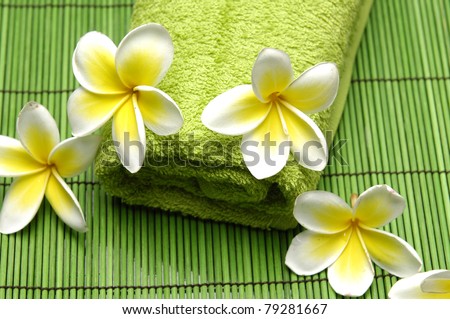 frangipani flower and green towel on green mat