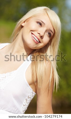 close-up portrait of beautiful young blond woman in white blouse at park