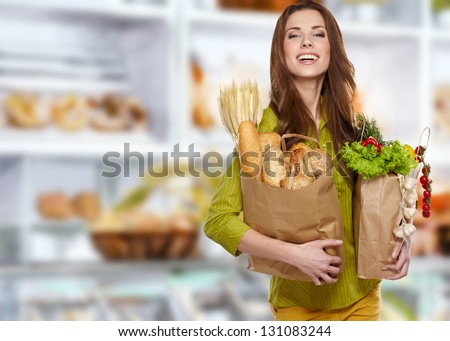 Young woman holding a grocery bag full of bread