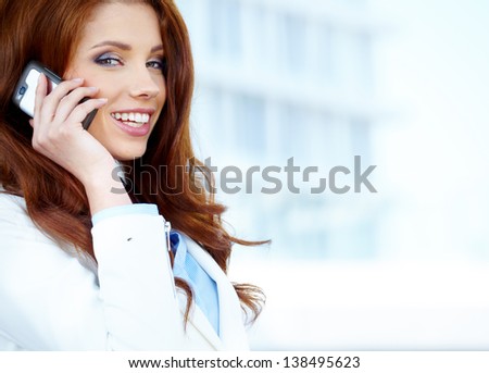Beautiful business woman talking on cell phone while looking at copyspace