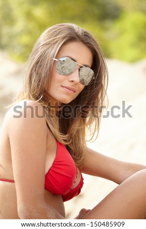 Young beautiful woman in red bikini and sunglasses at beach