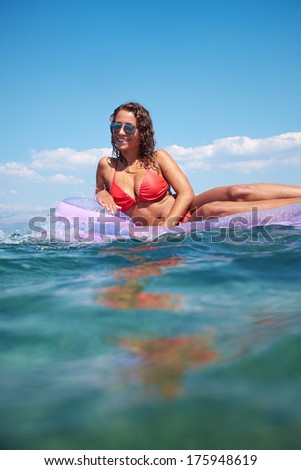 very happy woman on pink air bed in sea