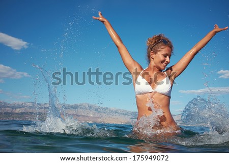 Happy young woman in sea with open hands.
