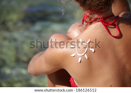 Woman With Suntan Lotion At The Beach In Form Of The Sun