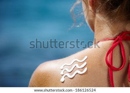 Woman with suntan lotion at the beach in form of a waves