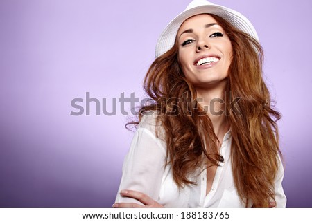 Fashion portrait of pretty woman wearing stylish hat. Young Caucasian female model posing in studio over violet  background.
