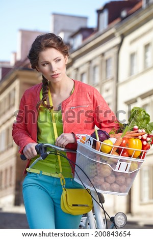 Pretty spring  woman with bicycle and groceries in old town street.