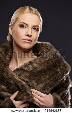 Woman in luxury fur coat. Vintage style. Brown background.