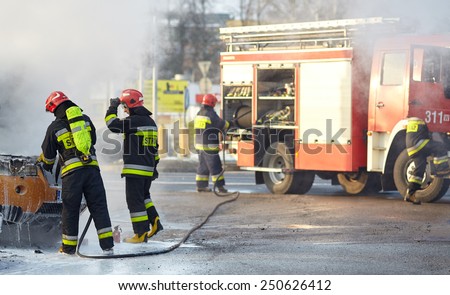 Warsaw, Poland - January 27, 2015: Firefighters are extinguishing a car on fire at main road in Warsaw.