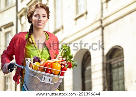 Pretty spring woman with bicycle and groceries in old town street.