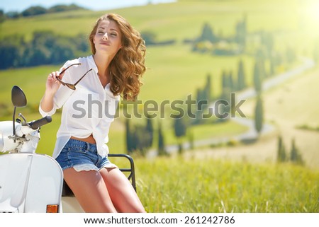 Young beautiful italian woman sitting on a italian scooter in Italy hills