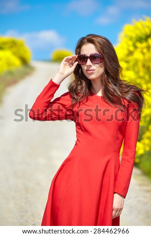 Beautiful woman in a red dress on a rural road in Italy