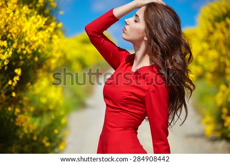 Beautiful woman in a red dress on a rural road in Italy