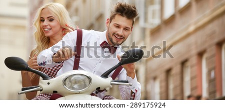 Fun ride. Beautiful young couple riding scooter together while happy woman bonding to her boyfriend and smiling