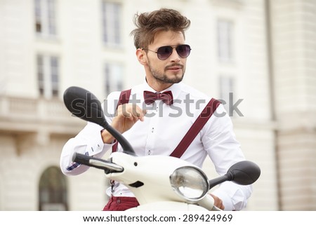 Hipster fashion men with scooter on a sunny day in the city