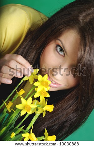 Spring portrait of young smiling woman with yellow flowers, green background