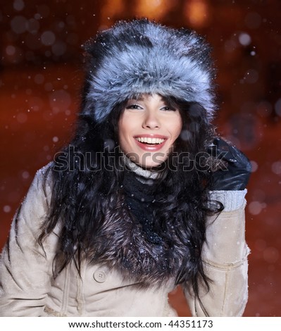 Smiling  woman in winter night city, snow background