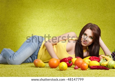 Young smiling woman with fruits and vegetables. Over green background